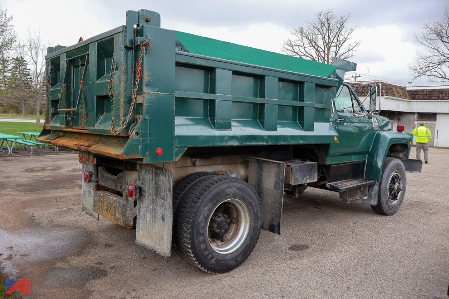 Dump truck rear and side view showing green Ford F800 dump bed and dual rear tires with mud flaps.