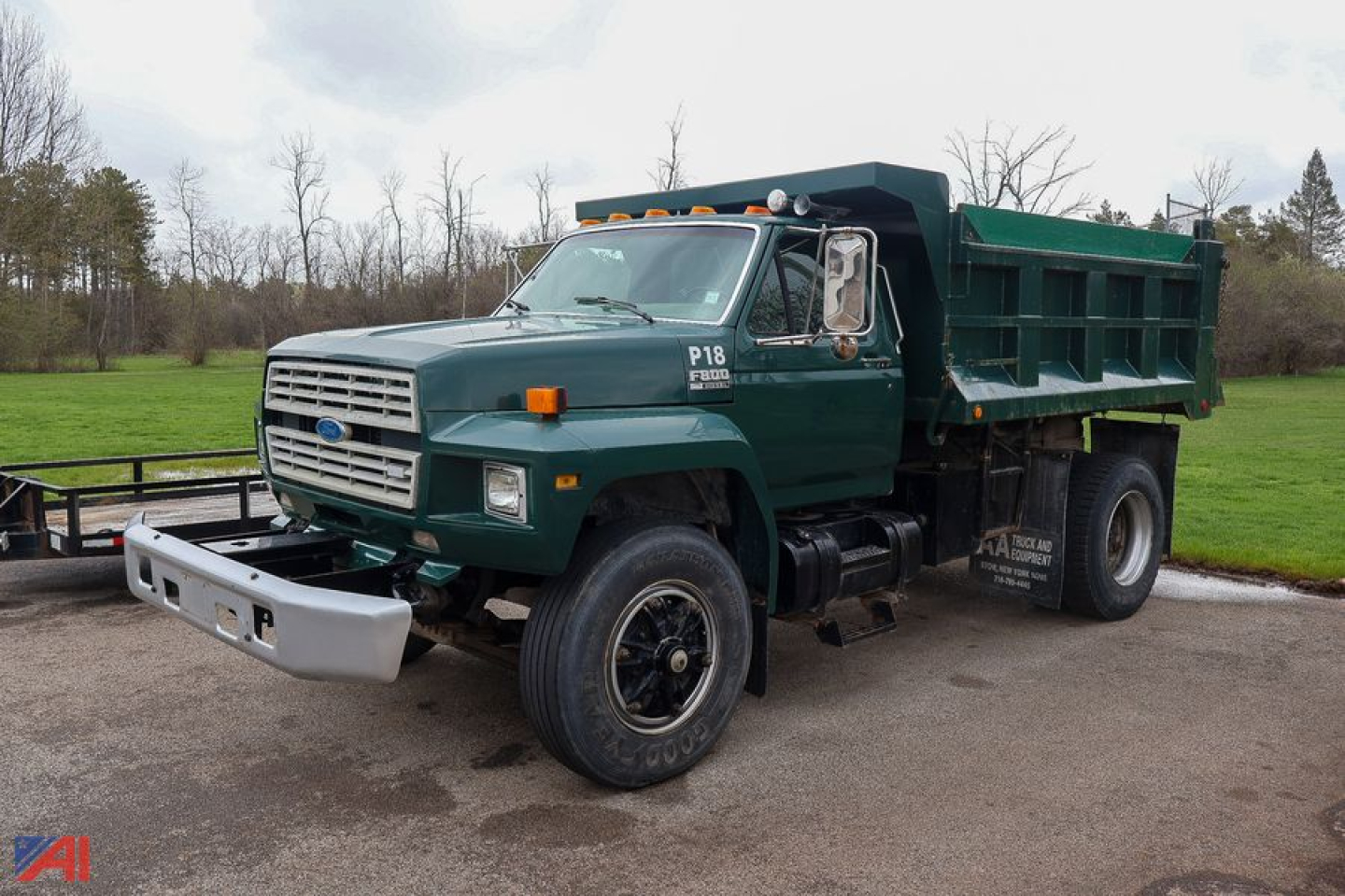 Ford F800 dump truck in green with front bumper, large dump bed, and dual rear wheels, side view.