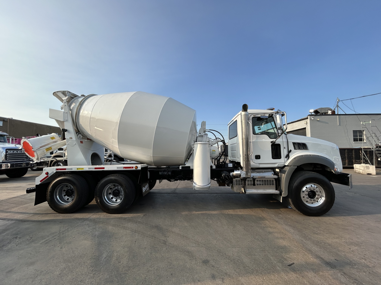 Concrete mixer truck side view with white cab and large rotating drum. No legible labels visible on the drum or cab.