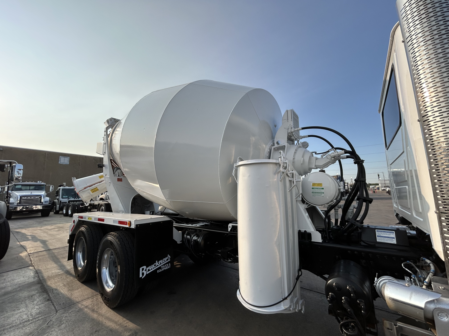 Mixer truck in-service showing cement mixer drum and hydraulic system with hoses and controls