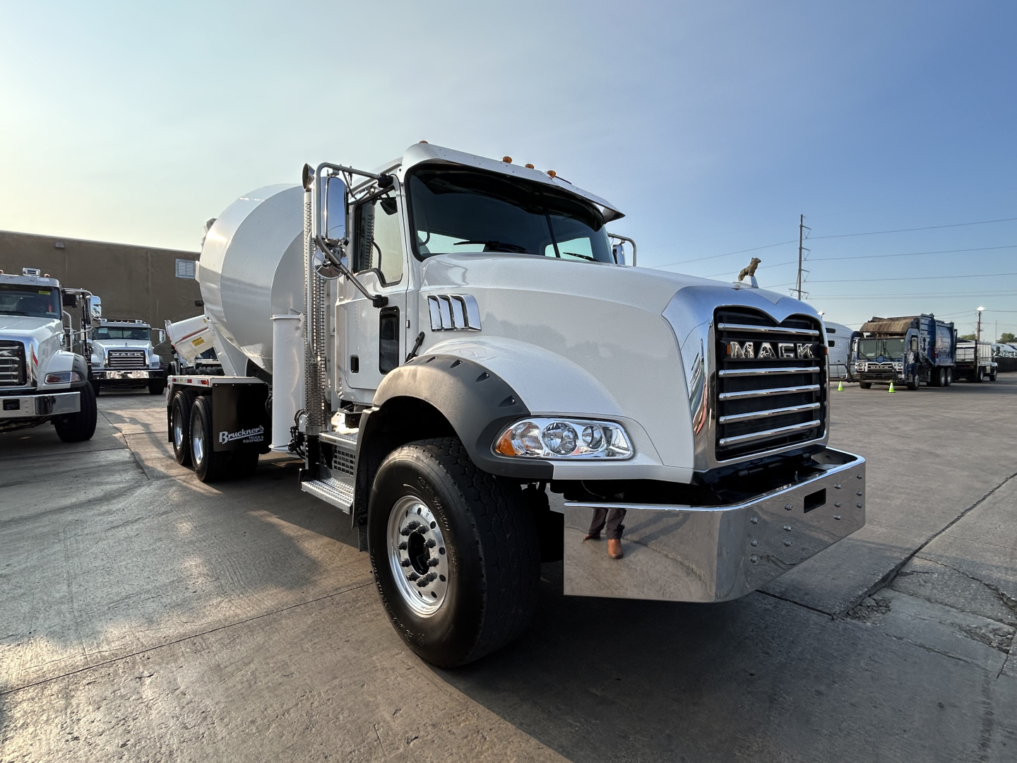 Mixer truck showing Mack GR64B front view with chrome grille and cement drum in background.