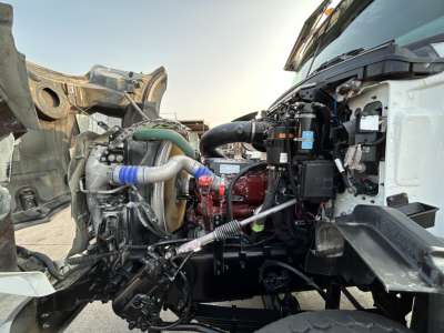 Truck engine bay of a 2020 Mack GR64B showing engine components, hoses, and wiring exposed in the front with bay access.