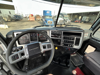 Mack GR64B truck interior showing steering wheel, dashboard with gauges, center console, and gear shifter.