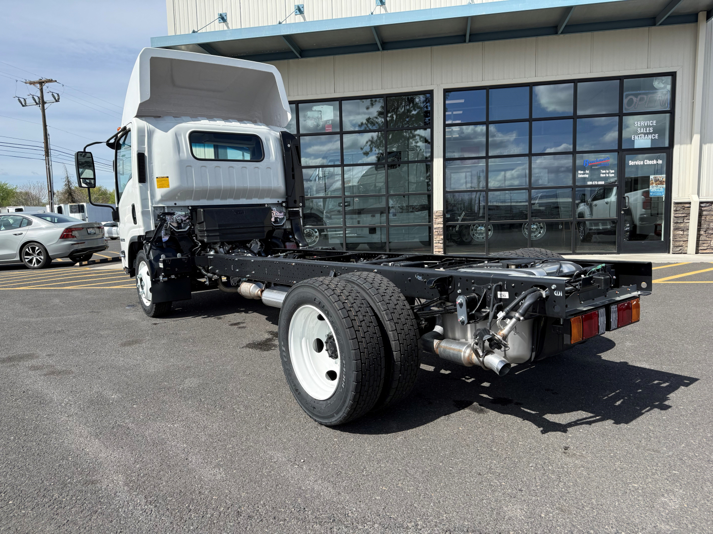 Isuzu NPRGASHD cab and chassis truck showing chassis frame and rear axle with dual rear wheels and exhaust pipe.