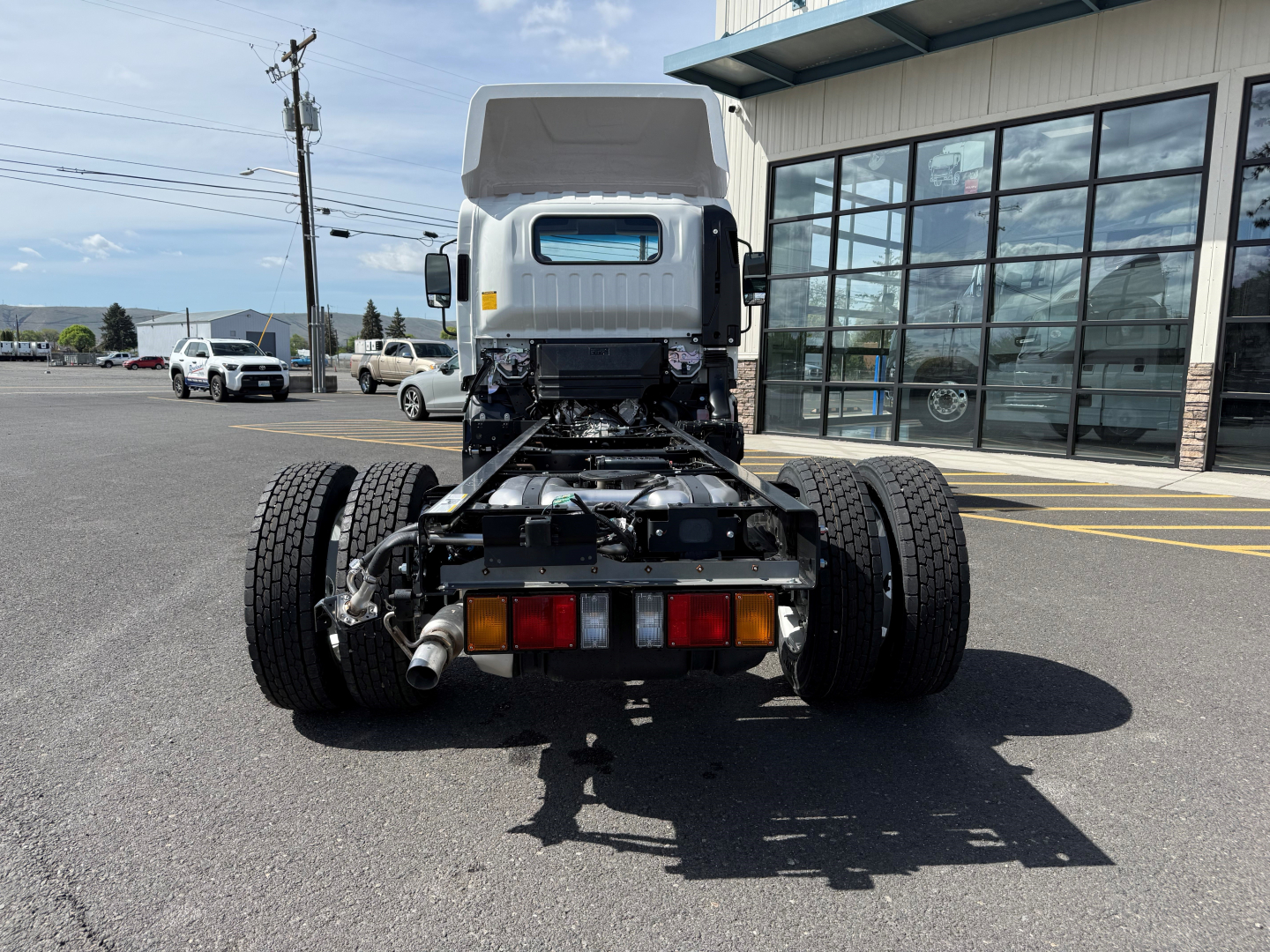 Isuzu NPRGASHD cab and chassis rear view showing chassis frame, dual rear axles, exhaust, taillights, and rear bumper.