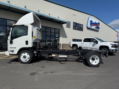 Isuzu NPRGASHD cab chassis on lot with white truck cab and chassis frame visible; factory building in background with Pohanka sign.