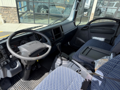 Isuzu NPRGASHD cab interior showing steering wheel, driver seat, and center console with dashboard and gear shifter.