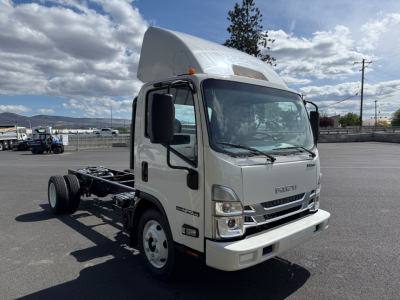 Isuzu NPRGASHD cab and chassis truck in a light color, front view with raised cab and chassis behind, clear blue sky.