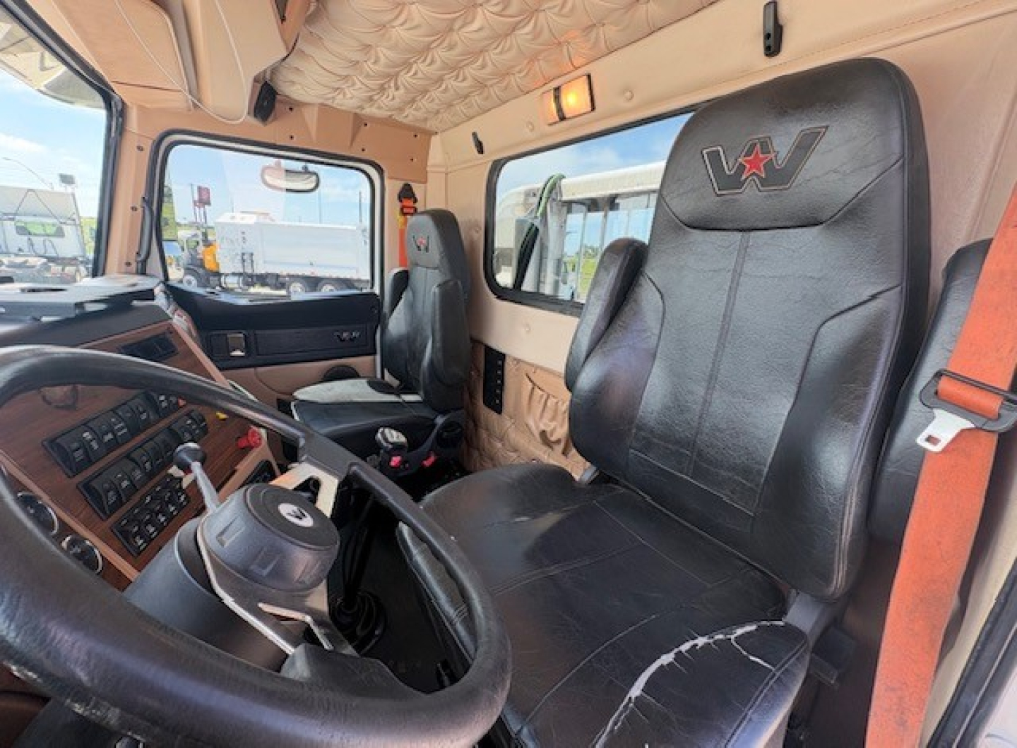 Cab interior of a 2020 Western Star 4700SF truck showing steering wheel, dashboard, driver seat with WV logo, and beige interior panels.