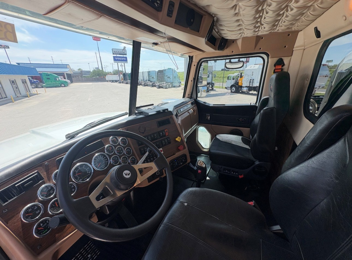 Western Star 4700SF cab interior dashboard view with steering wheel, multiple analog gauges, and beige upholstery.