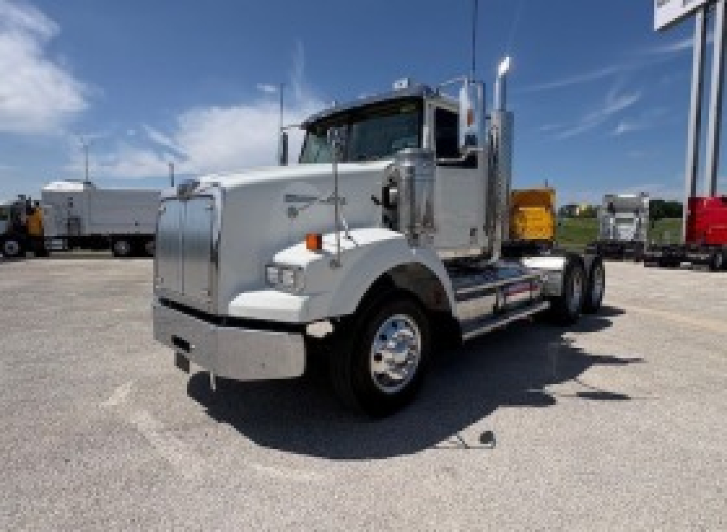 Truck image: 2020 Western Star 4700SF conventional daycab, front angle view, chrome bumper, dual rear axles, silver exterior, VIN plate area not legible, dealership lot in background.