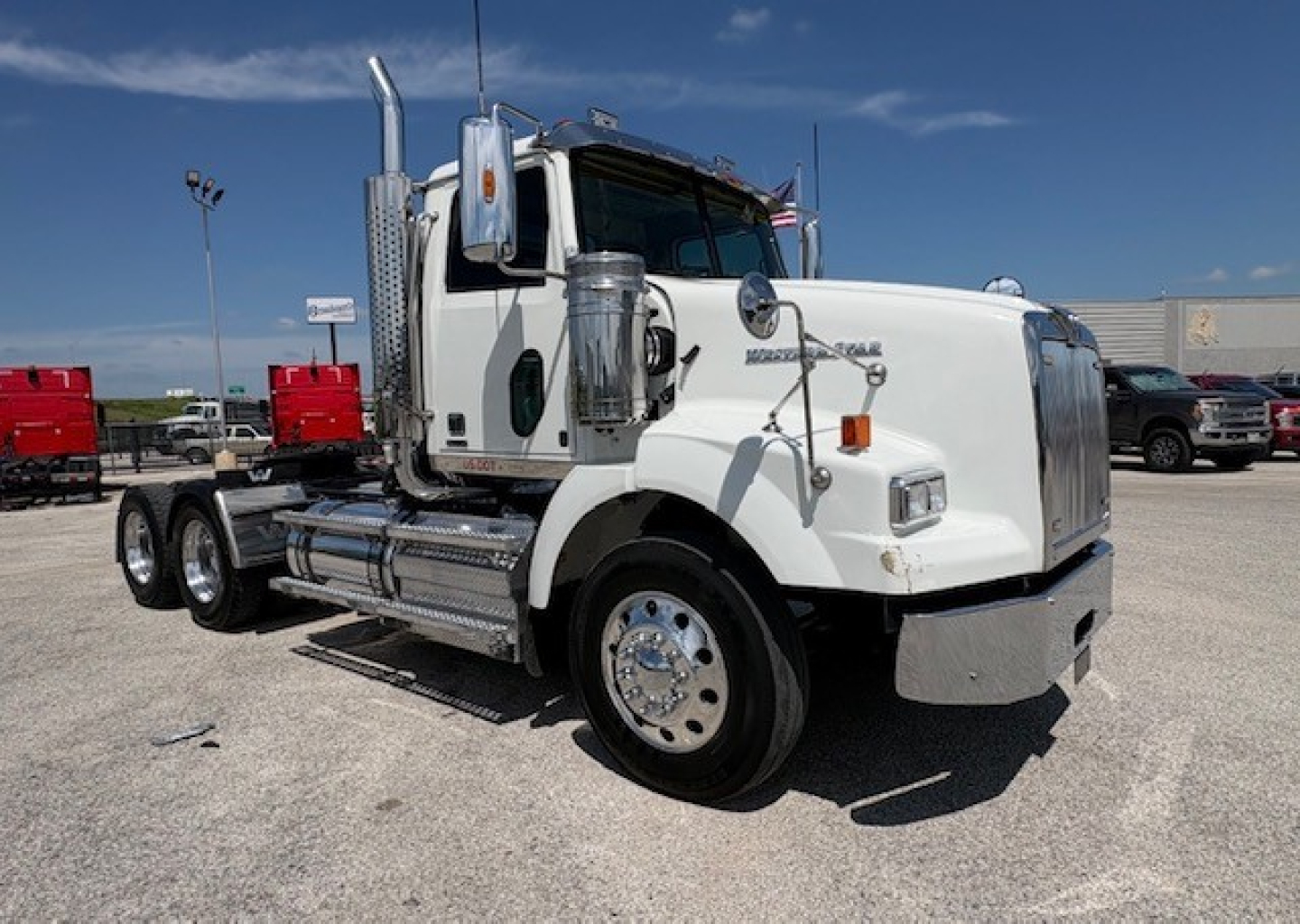 Western Star 4700SF daycab truck with chrome exhaust stacks, round mirrors, and polished fuel tanks. Front view showing cab and dual rear axles.