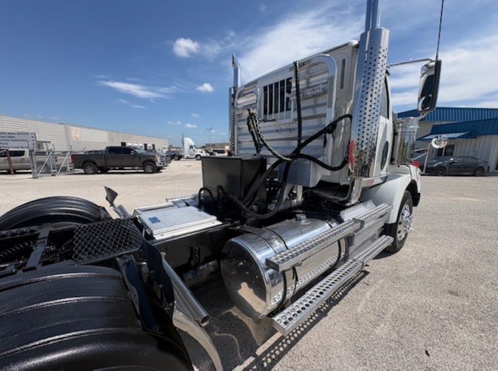 Technician view of a 2020 Western Star 4700SF truck cab and side fuel tanks. Visible components include chrome cylindrical fuel tanks, steps, and cab with exposed wiring harnesses.