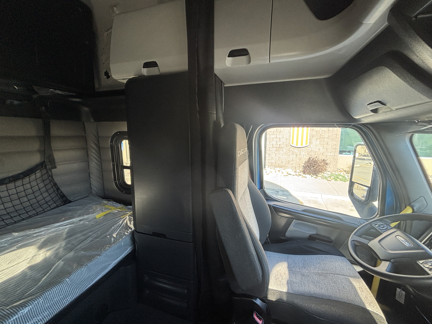 Truck cab interior of a Freightliner PT126064ST with sleeper, front seats, dashboard, and overhead bunk area visible.