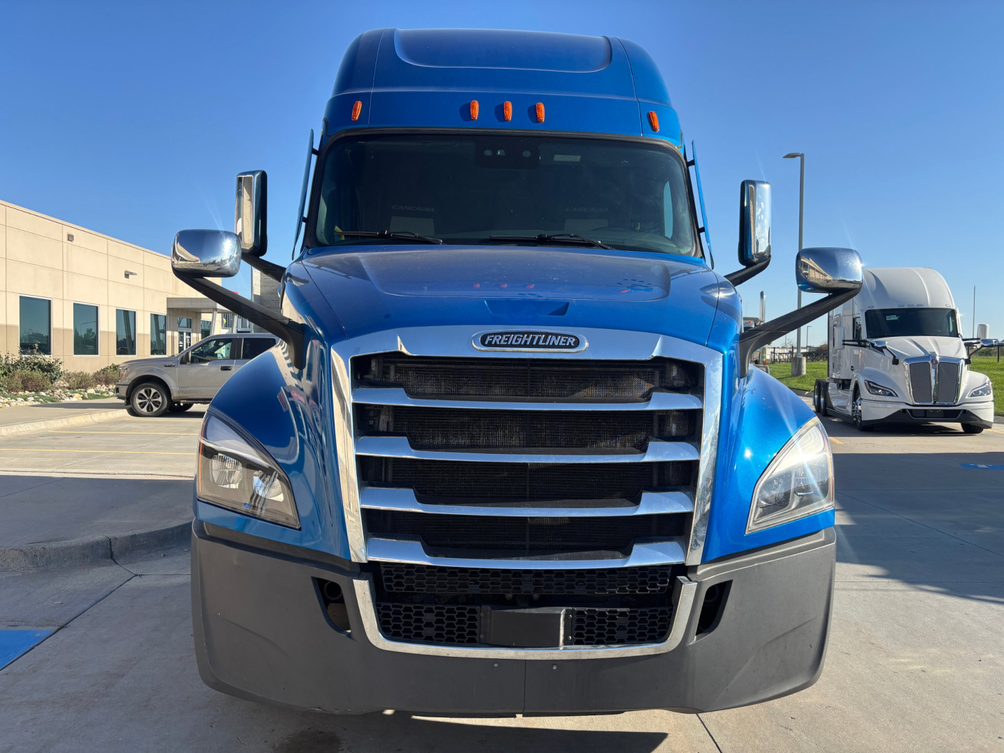 Front view of a blue Freightliner PT126064ST conventional sleeper truck showing chrome grille, bumper, and large windshield.