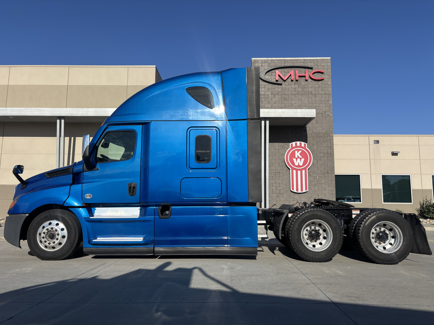 Freightliner PT126064ST sleeper tractor in blue parked outdoors showing cab and rear sleeper with MHC sign