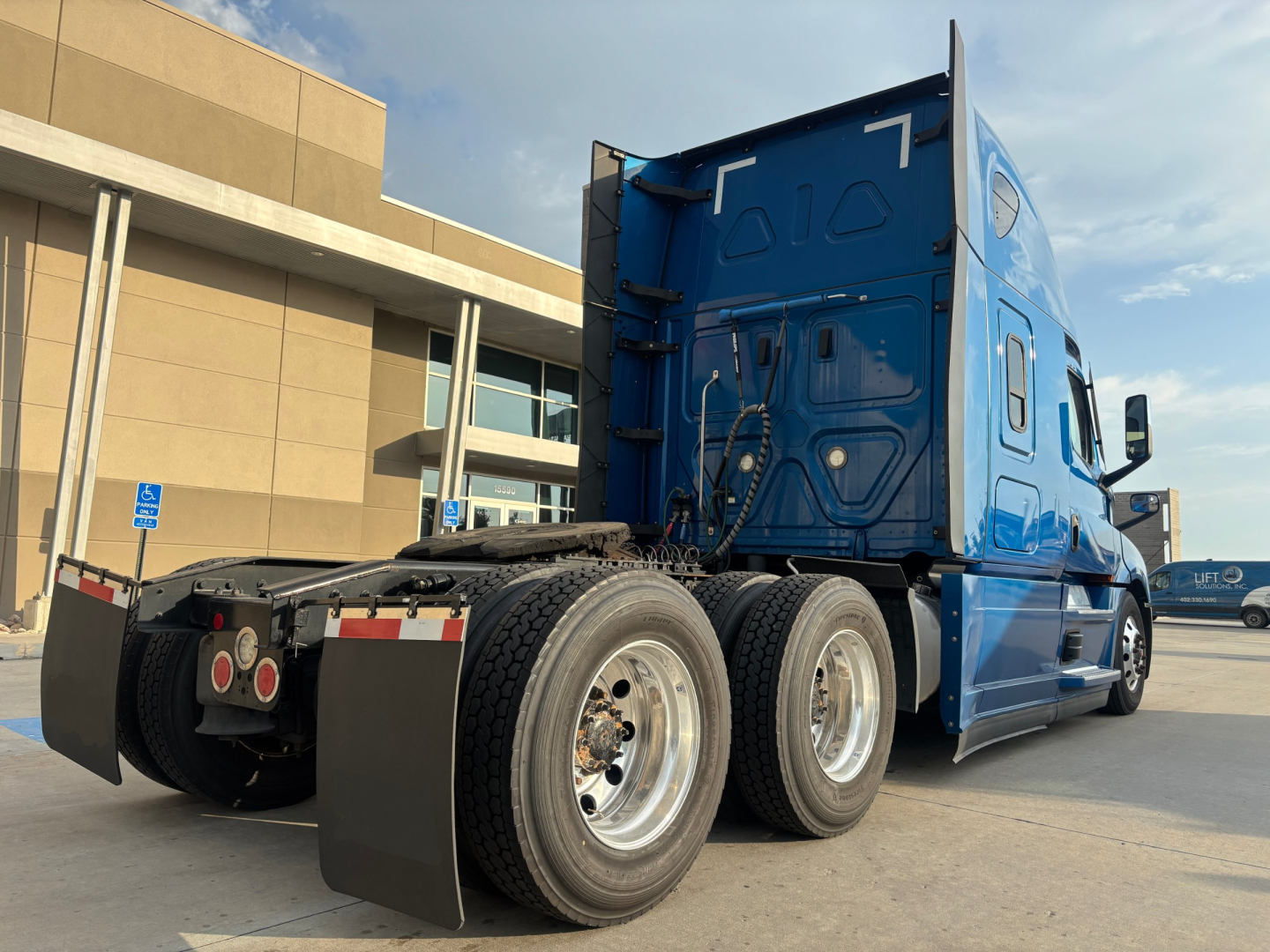 Rear and side view of a blue Freightliner PT126064ST truck tractor showing rear dual wheels and sleeper cab. Visible text not legible on image.