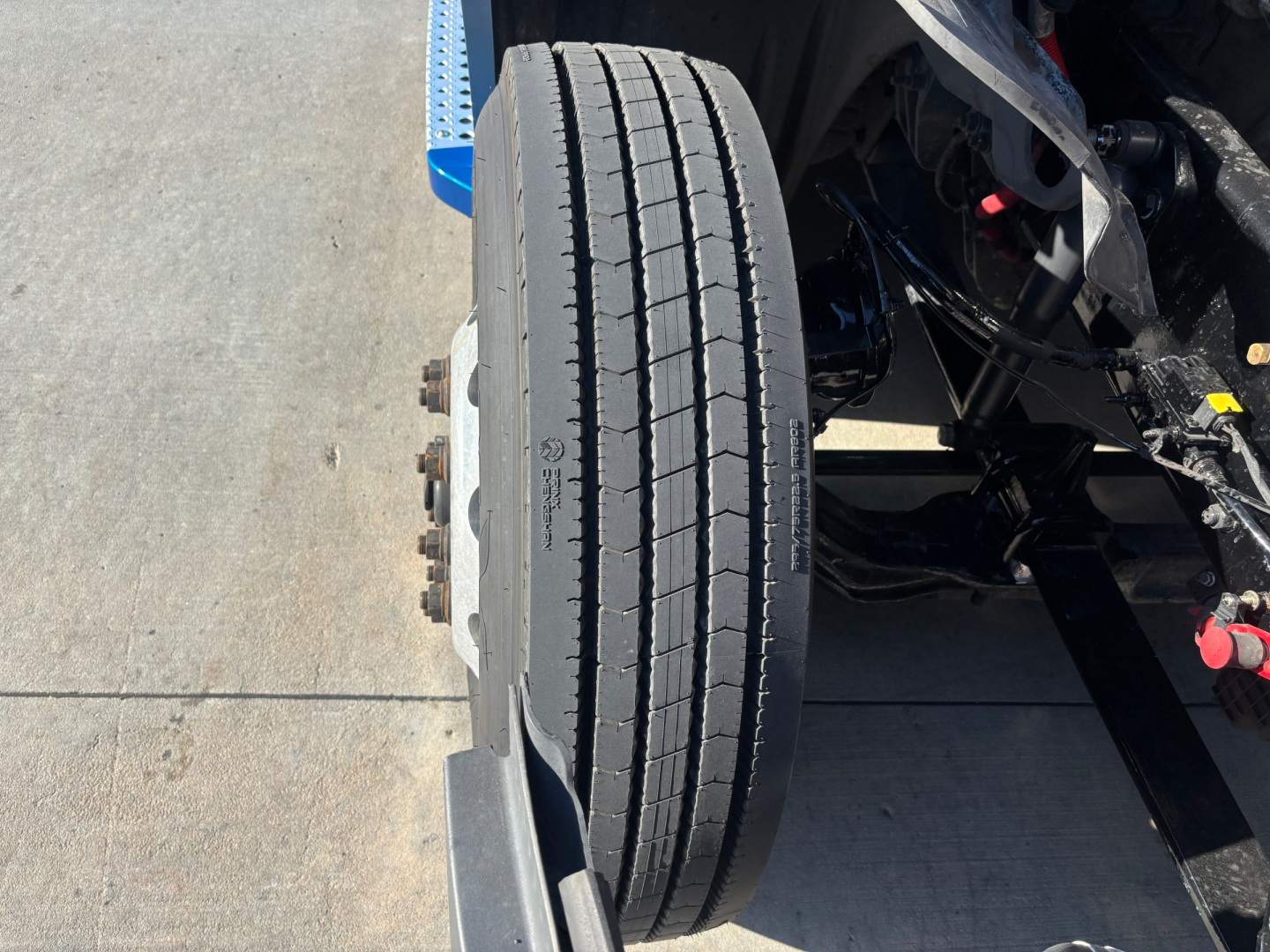 Wheel and tire assembly of a Freightliner PT126064ST truck showing front dual wheel hub area and tire tread with visible suspension components.
