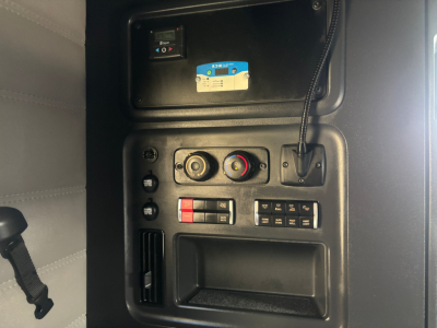Cab interior dash controls with blue label card and red/black switches, CT switches, and a storage slot in view.