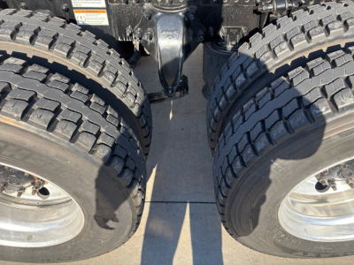 Freightliner PT126064ST chassis showing dual rear axles with large off-road tires and center drivetrain area.