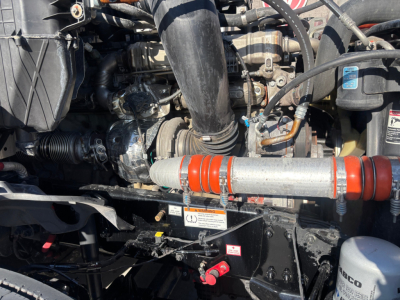 Engine bay of a Freightliner PT126064ST showing hoses, belts, and engine components with orange-red coolant hose and black intake piping.