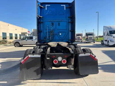 Rear view of a blue Freightliner PT126064ST tractor with dual rear axles and mud flaps, showing electrical connectors and fifth wheel area.