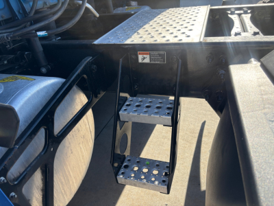 Step ladder mounted beside fuel tank on Freightliner PT126064ST cab area showing perforated metal steps and chassis plates.
