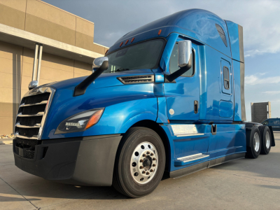 Freightliner semi truck cab in blue, front-left view, showing windshield, mirrors, side steps, and wheel. No textual labels visible on the truck in this image.