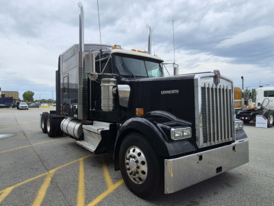 Kenworth W900L truck in black with chrome grille and bumper, side view showing sleeper cab, dual exhaust stacks, large fuel tanks, and chrome wheels.