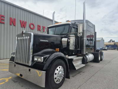 Kenworth W900L truck in front of dealership showing grille, chrome bumper, and exhaust stacks.