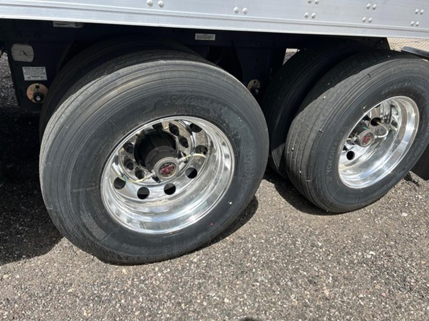 Two rear axles of a utility trailer with large dual tires and polished rims, part of a reefer trailer undercarriage.