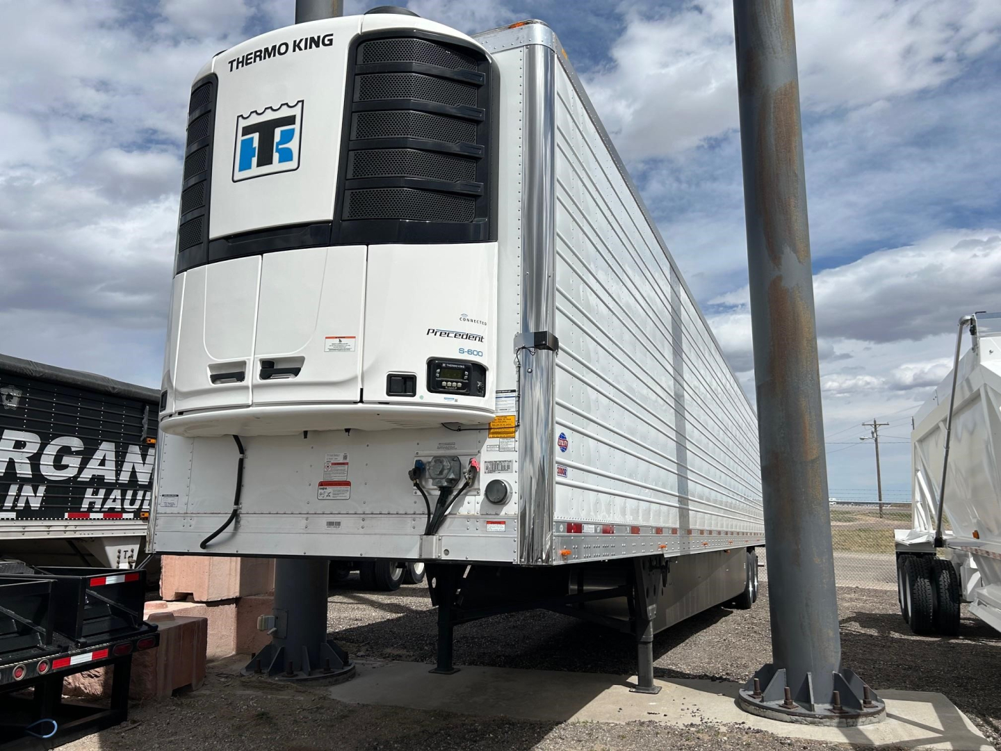 Utility 3000R trailer with Thermo King refrigeration unit showing ref-freeze system and aerodynamic front. Side view of silver trailer on wheels with support legs visible.