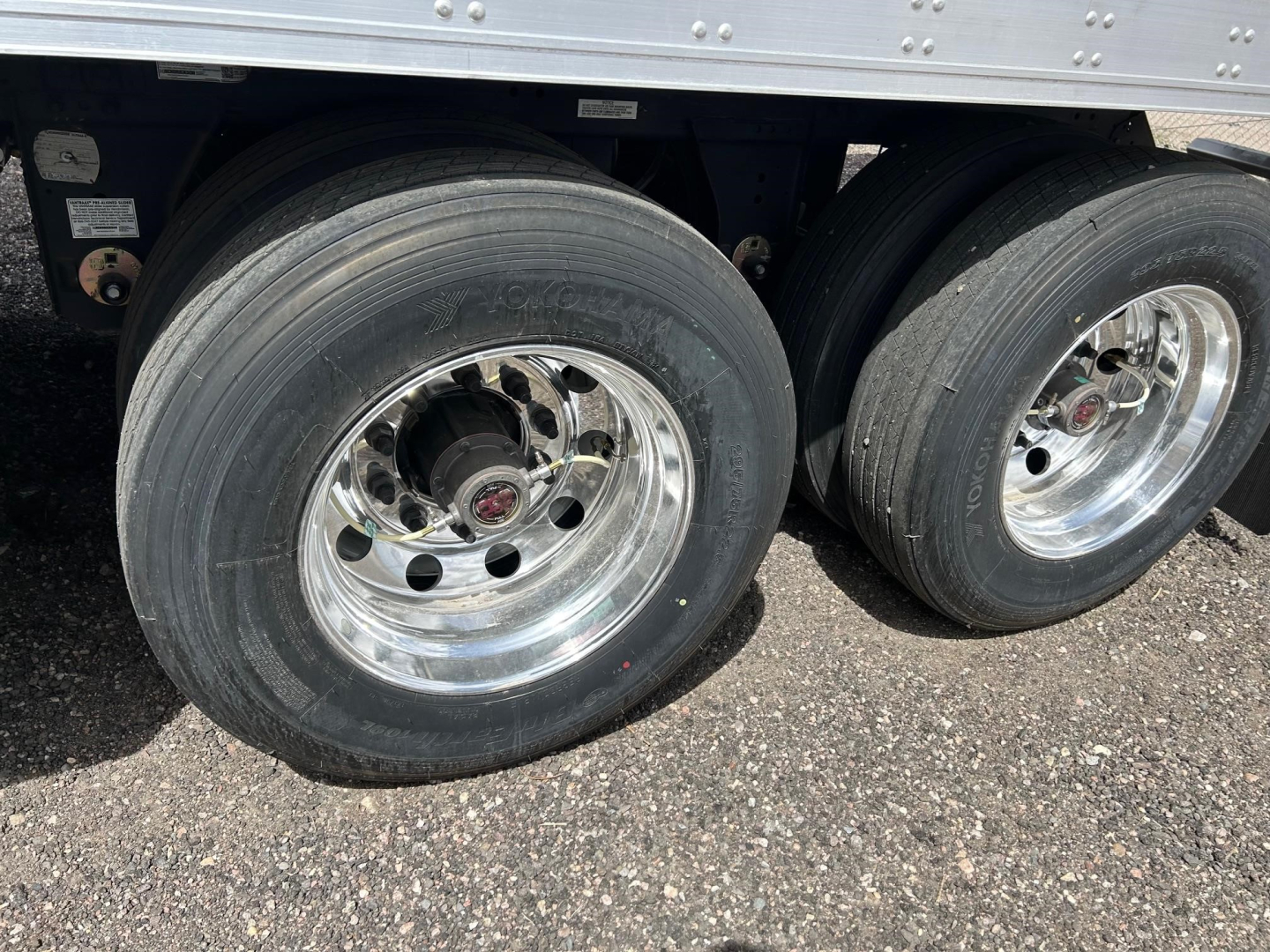 Trailer wheel pair showing dual rear axles with polished rims and heavy-duty tires under a reefer trailer.