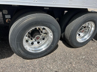 Two rear axles of a utility trailer with large dual tires and polished rims, part of a reefer trailer undercarriage.