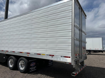 Utility trailer with aluminum side panels and dual rear doors, 3-axle setup, chrome wheels, and rear underride bumper.