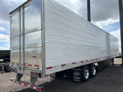 Trailer side and rear showing Utility 3000R aluminum contractor trailer with tandem axles, diamond plate rear doors, and reflective tape along lower edge.