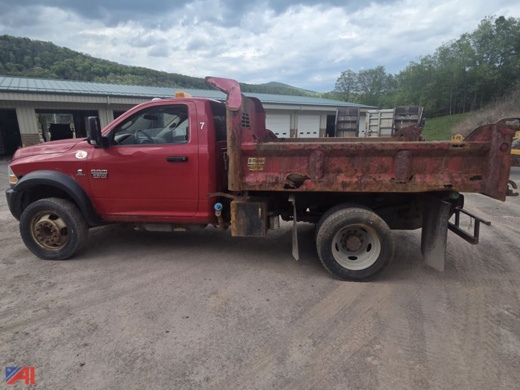 Ram 4500 dump truck side view with red cab and long brown dump bed. Visible text includes DODGE RAM 4500 badge on door and side step areas.