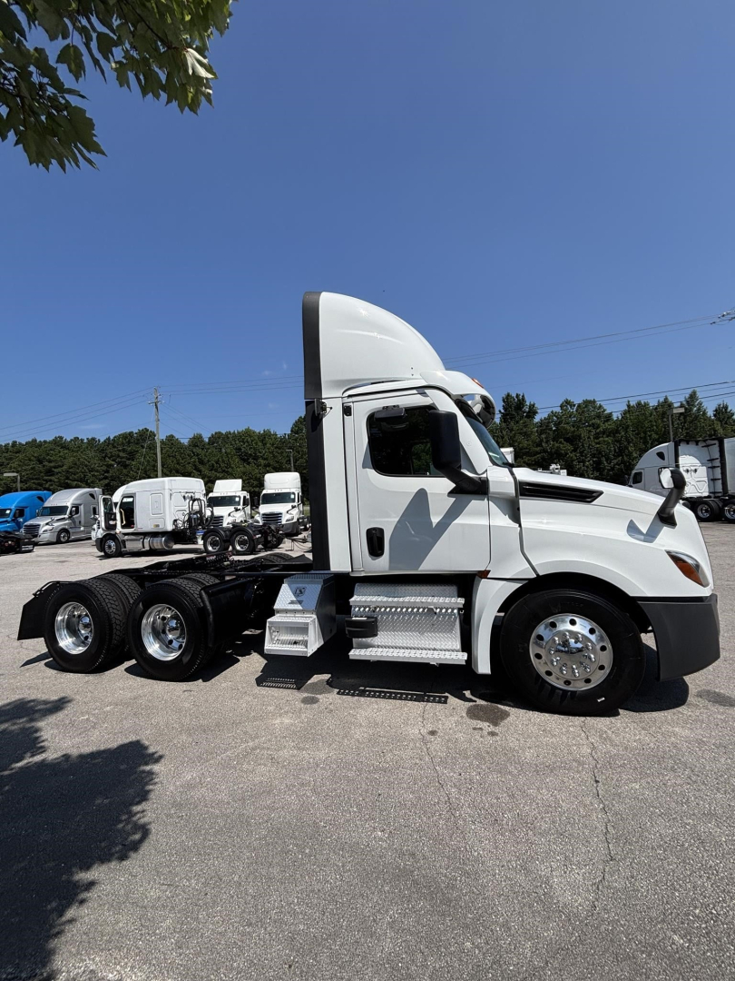 Truck cab side profile of a 2023 Freightliner Cascadia 126 with sleeper hood, chrome wheels, dual rear axles, and side steps.