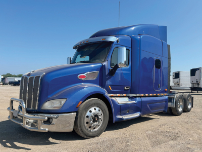 Peterbilt 579 UltraCab conventional sleeper truck in blue, side view showing front grille, chrome bumper, and dual rear axles.