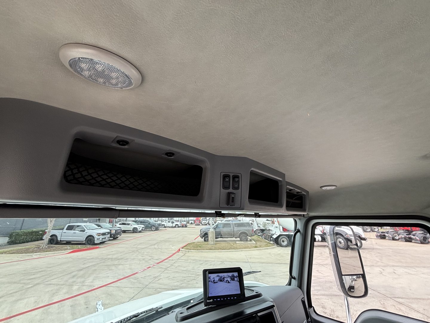 Interior of a 2026 Mack MD7 cab showing overhead storage and dash area with a small monitor resting on the dash.
