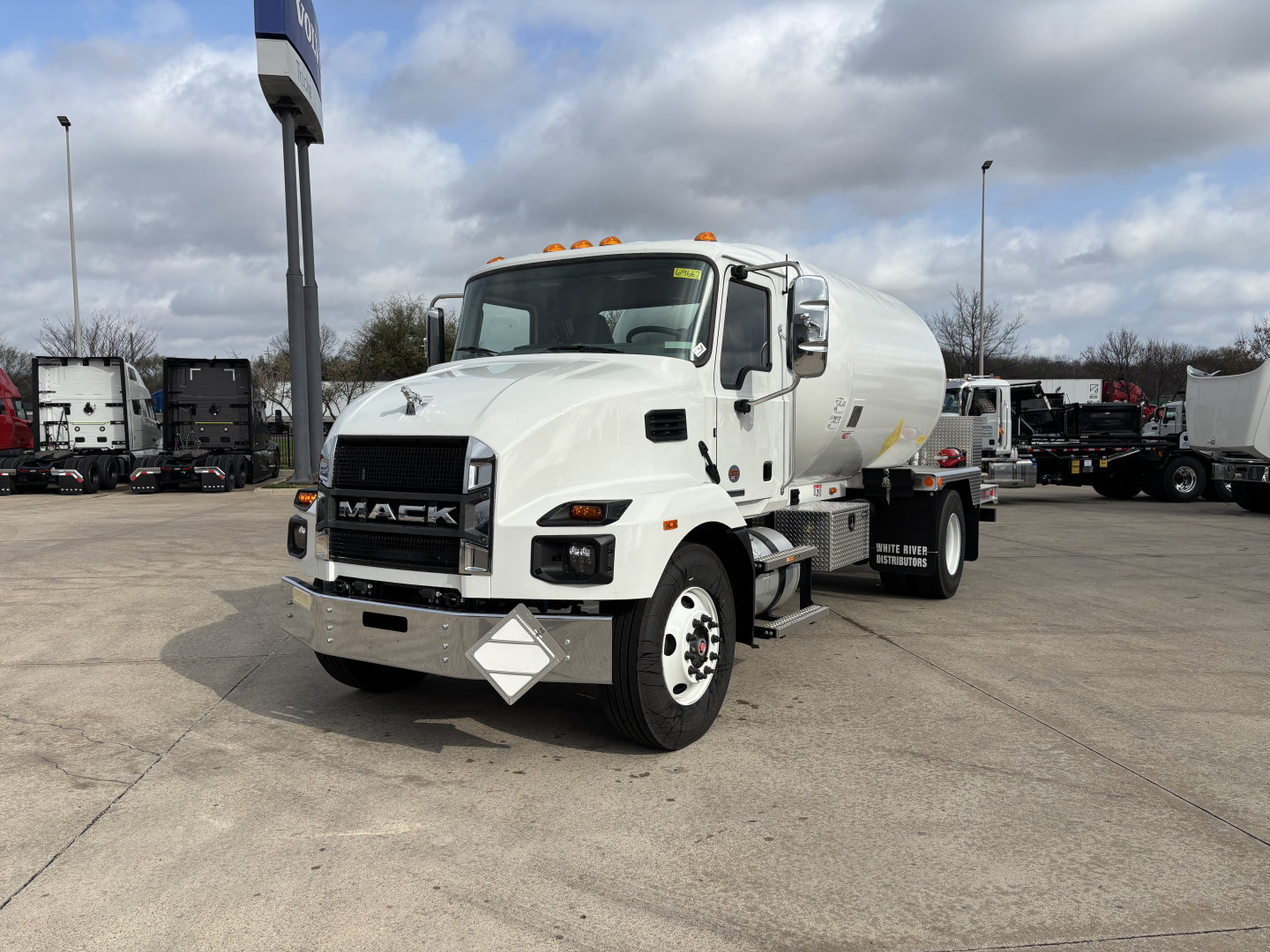 Mack MD7 concrete mixer truck in white with front grille and cab detail, showing cement mixer behind the cab and diamond plate bumper.