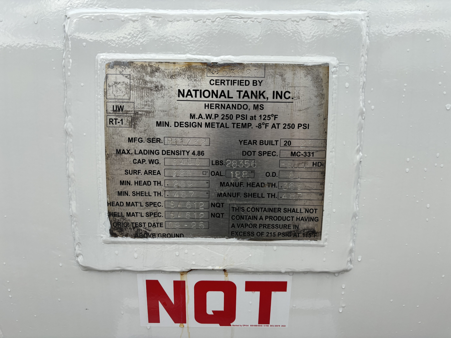 Certified by National Tank, Inc. plate on a white surface with NQT marking in red letters below and a vehicle VIN plate visible.