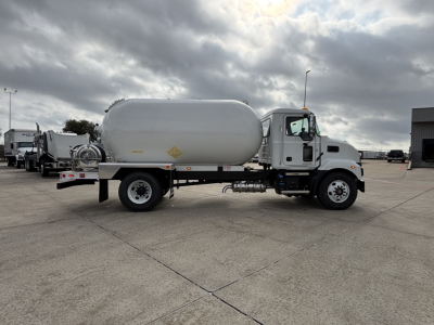 Tank truck with cylindrical tank mounted on frame, white cab, side view