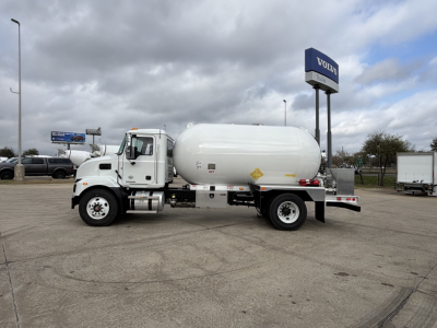 New 2026 Mack MD7 vacuum or liquid tank truck in a dealership lot, white cylindrical tank mounted on chassis, with Volvo sign in background.