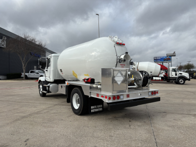 Tank truck rear/left side showing large cylindrical tank and rear platform; diamond hazard placard on tank; white cab; rear lights and metal fenders; company text 'WHITE RIVER DISTRIBUTORS' on mudflap