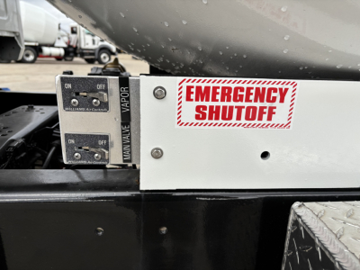 Emergency shutoff switch and control levers on Mack MD7 component visible in engine area with label EMERGENCY SHUTOFF and MAN VALVE/VAPOR text.