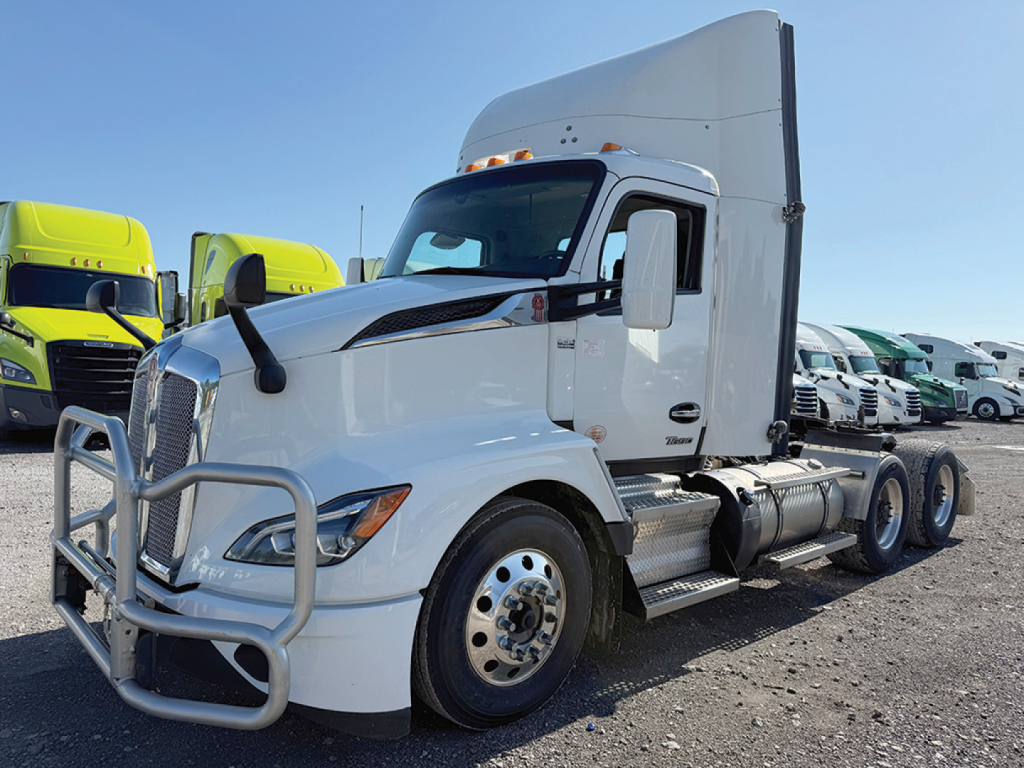 Kenworth T680 Next Gen in white, left-side view showing cab with aerodynamic sleeper, front bumper grille guard, dual rear axles, and large mirrors.
