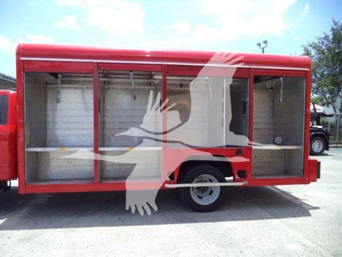 Open beverage truck body with side compartments and empty shelves; red exterior, single rear wheel visible, cargo area exposed.