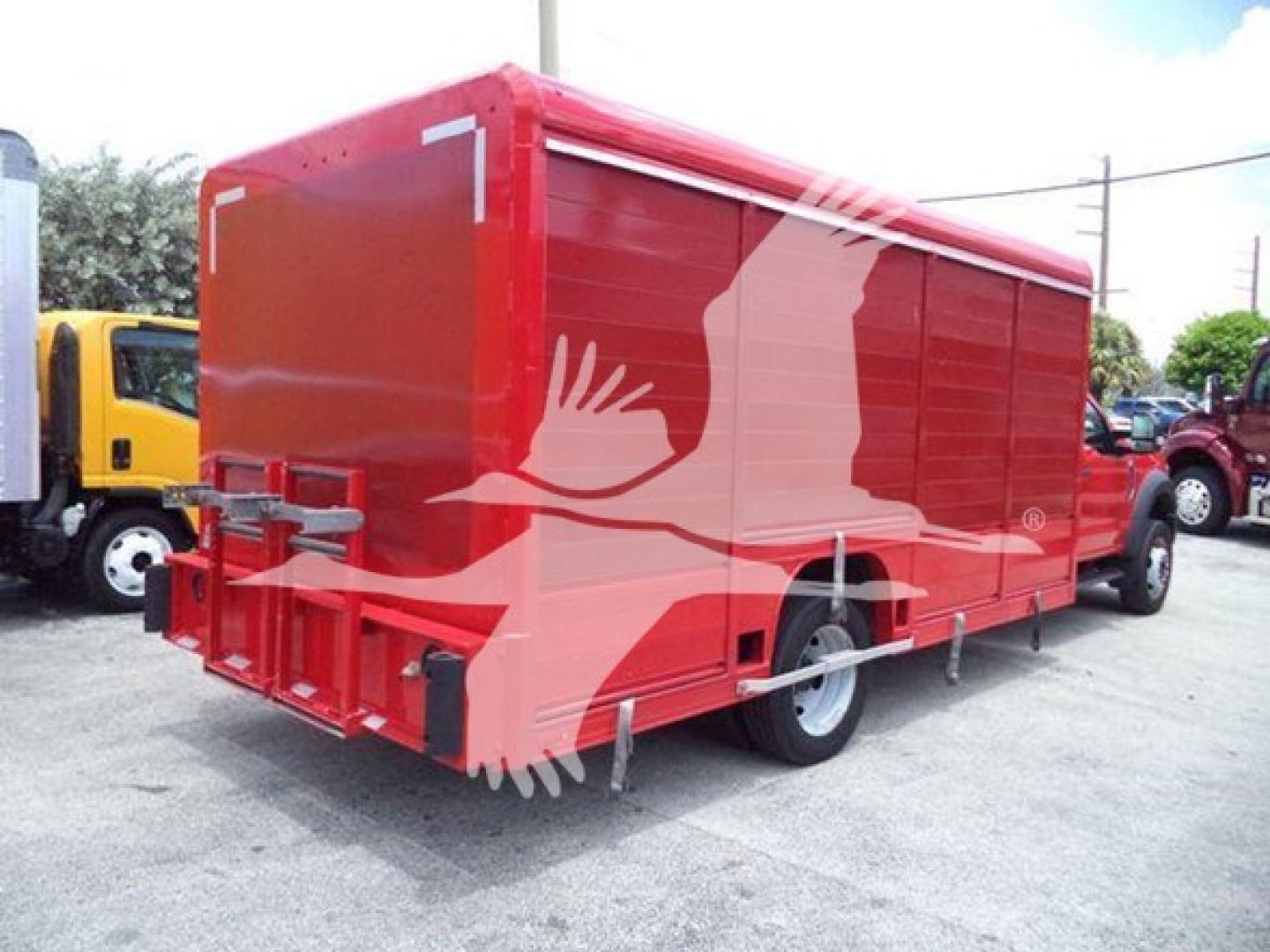 Ford F-550 box truck with red cargo body and white bird silhouette artwork, rear view showing bumper and hinges.