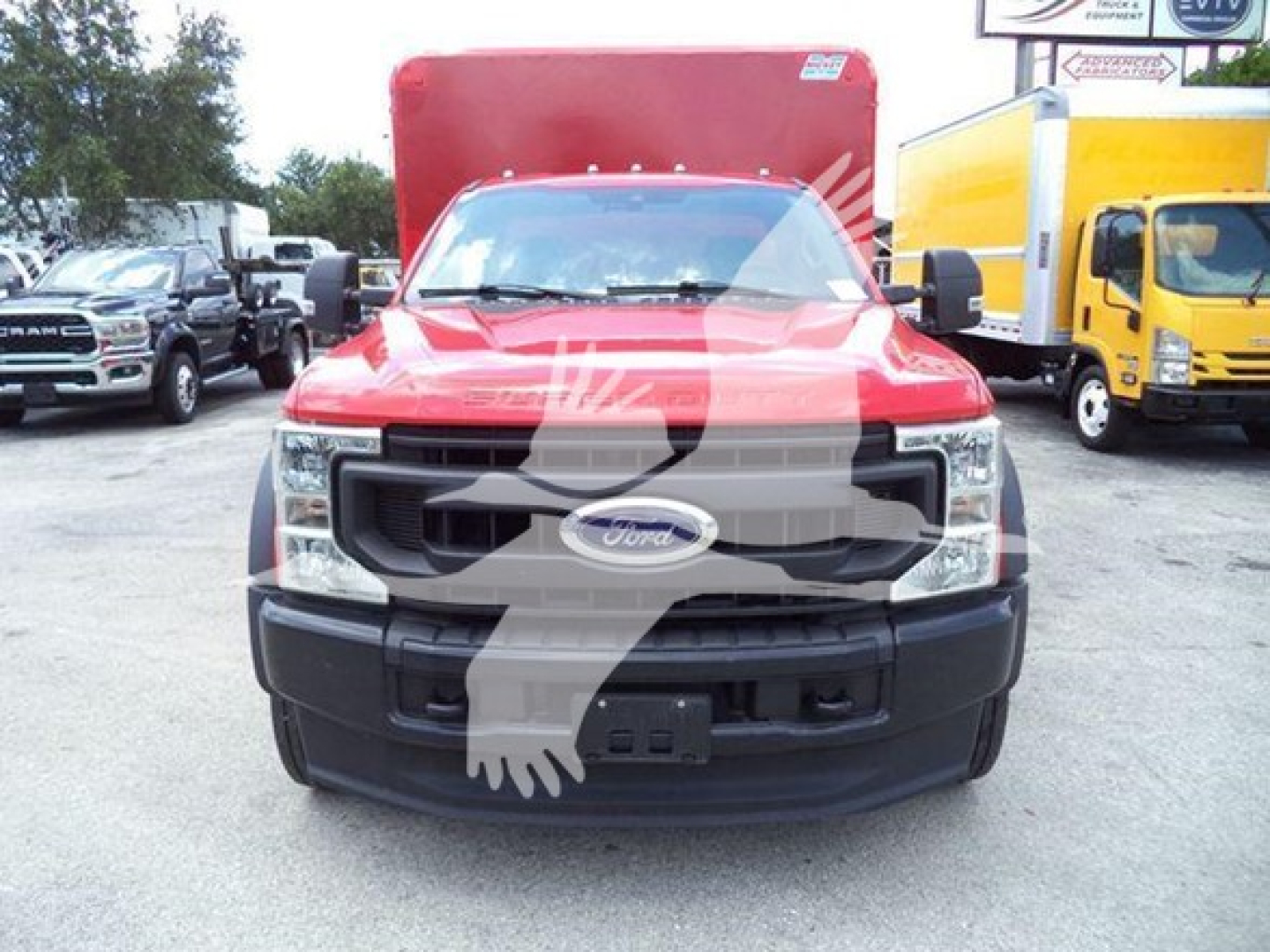 Front view of a red 2020 Ford F-550 truck with black grille and bumper, F-350-like headlight assembly visible, Ford emblem on grille. Other trucks parked nearby.